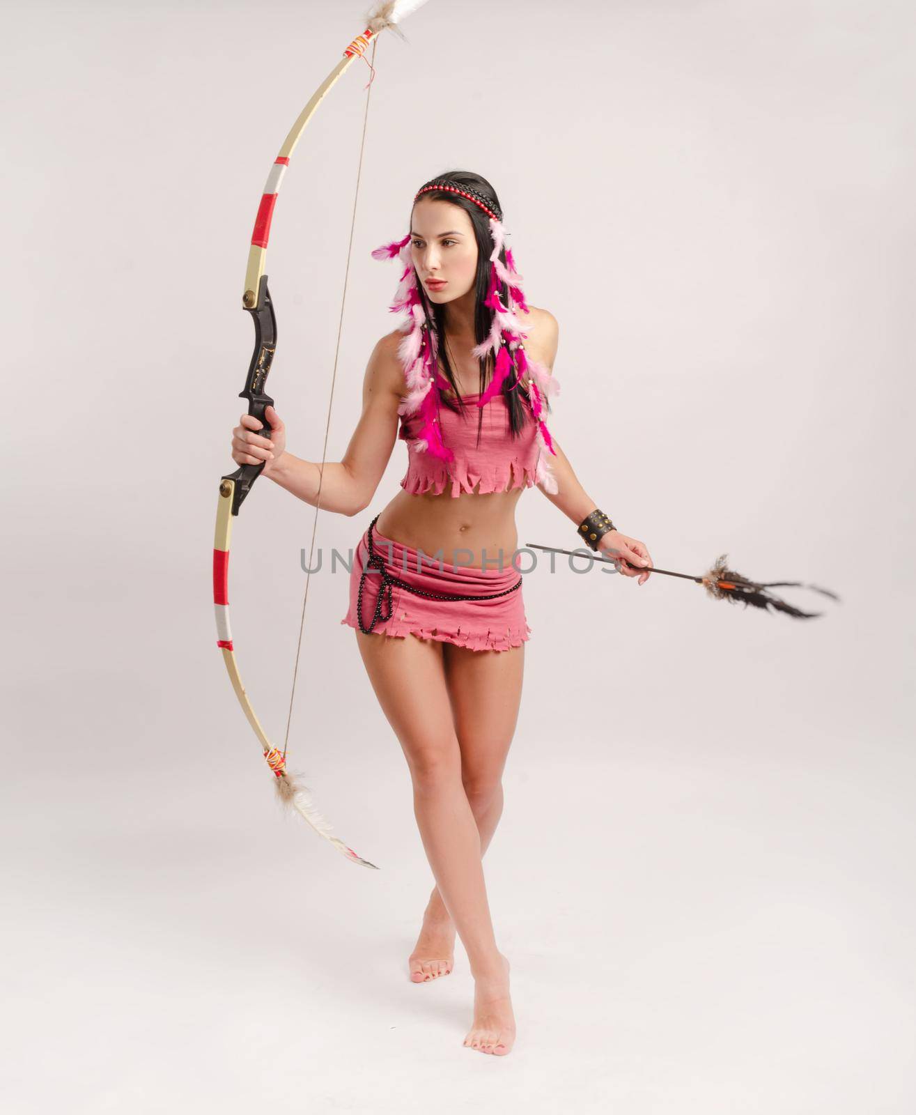 slender woman in an Amazon costume with a bow and arrow in her hands by Rotozey