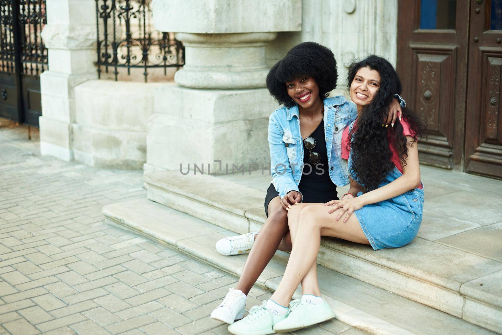 Happy young African American woman smiling, hugging Indian girlfriends and looking at the camera. Multinational friendship concept.