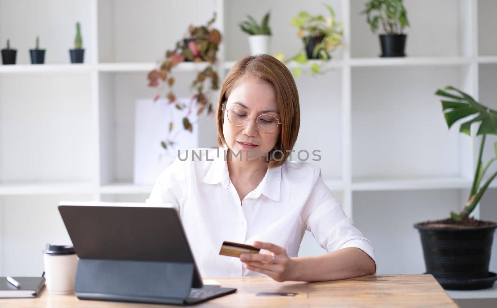 Asian senior woman using a laptop PC with a credit card. by wichayada