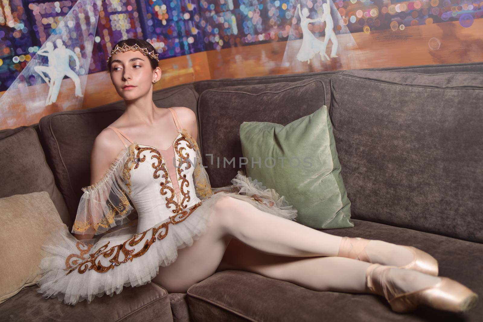 charming ballerina in a wearing a white tutu sits on the Sofa by Nickstock