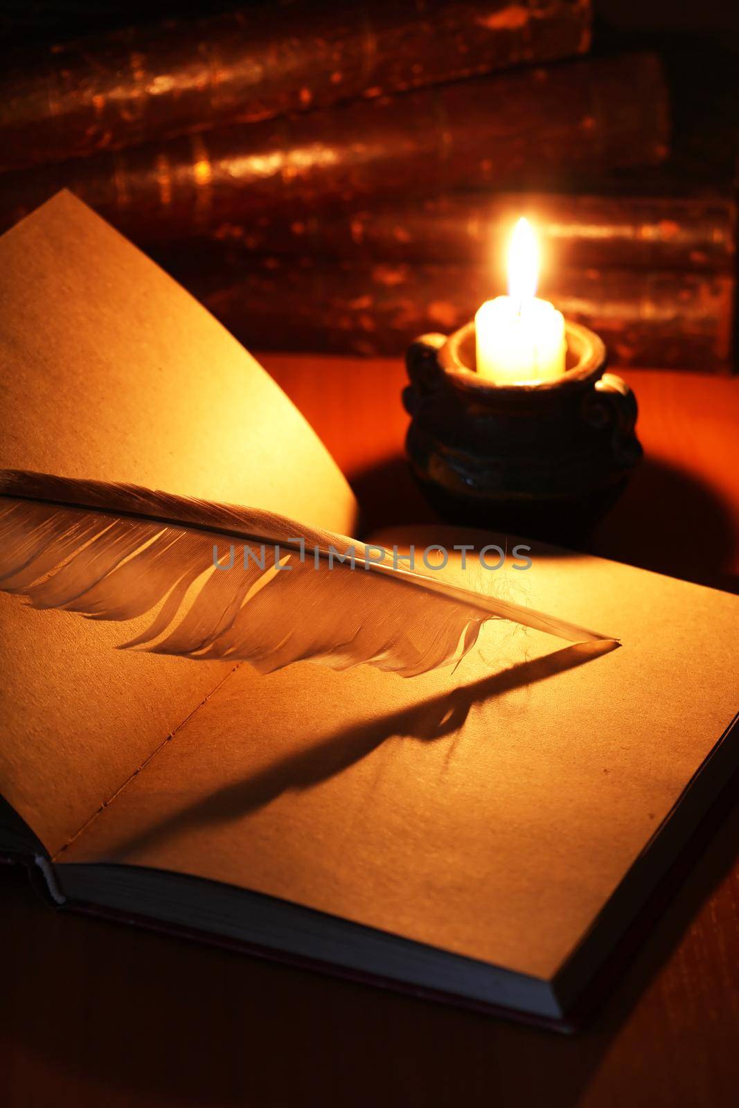 Vintage still life with open book and quill pen near lighting candle