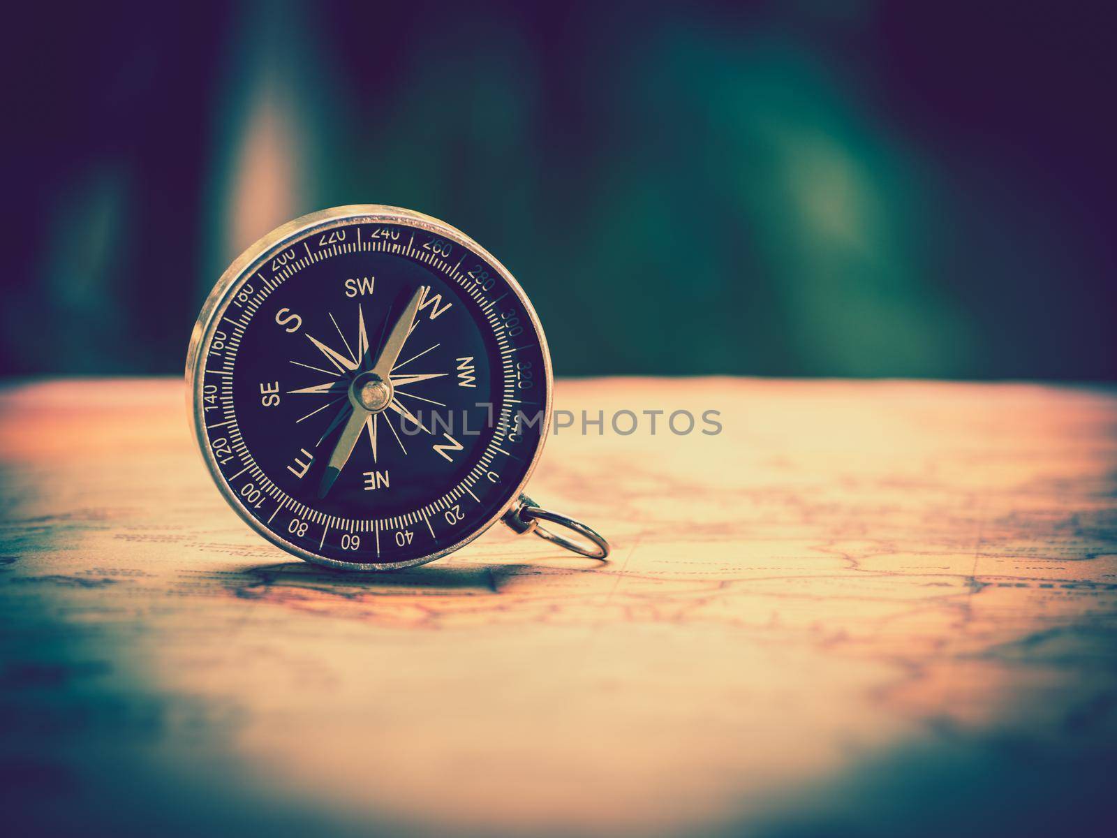 The compass is placed on the ancient or vintage world map . Travel geography navigation concept background.
