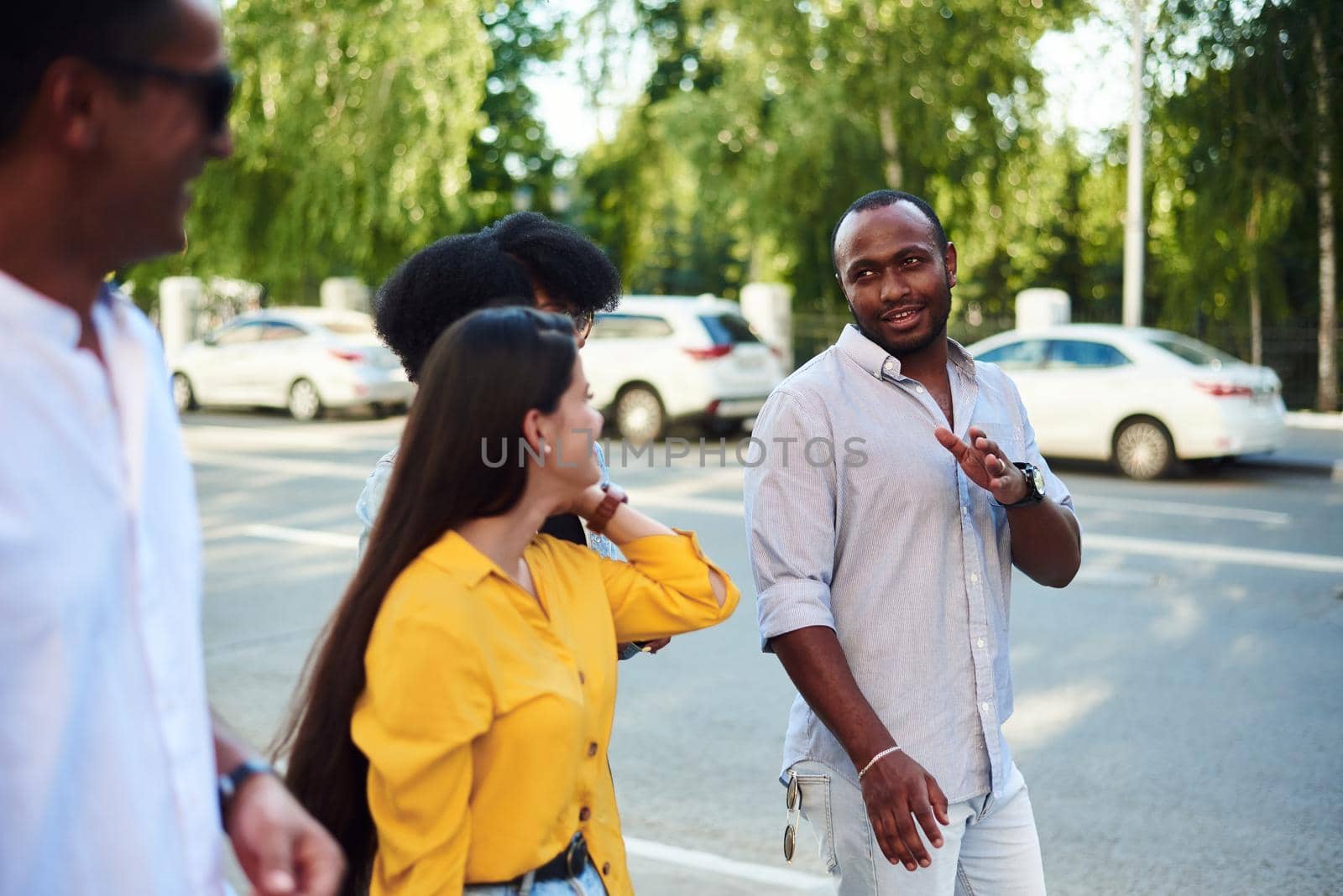 Group of friends on walk outside together. Happy young men and women hiking in city together on a summer day.