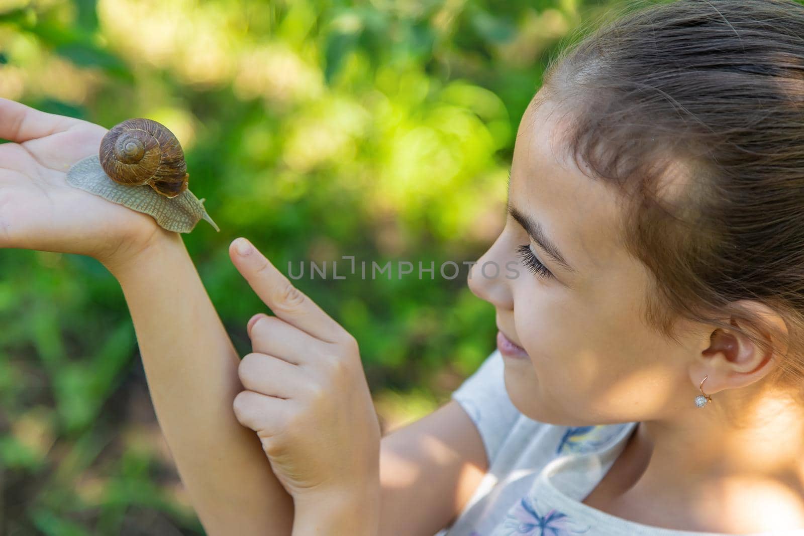 The child examines the snails on the tree. Selective focus. by yanadjana