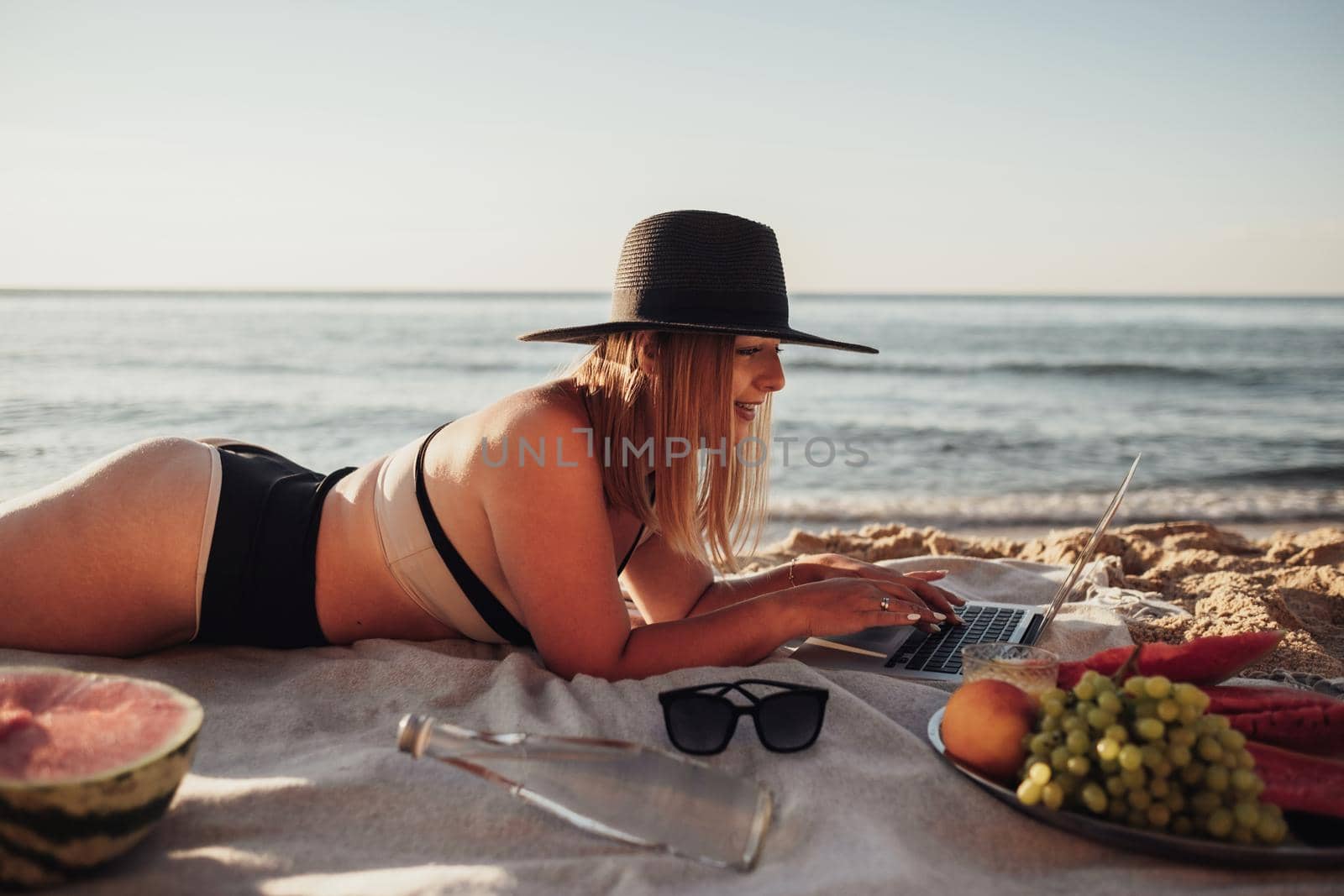 Young Woman Dressed in Swimsuit Working on Laptop During Picnic by Sea