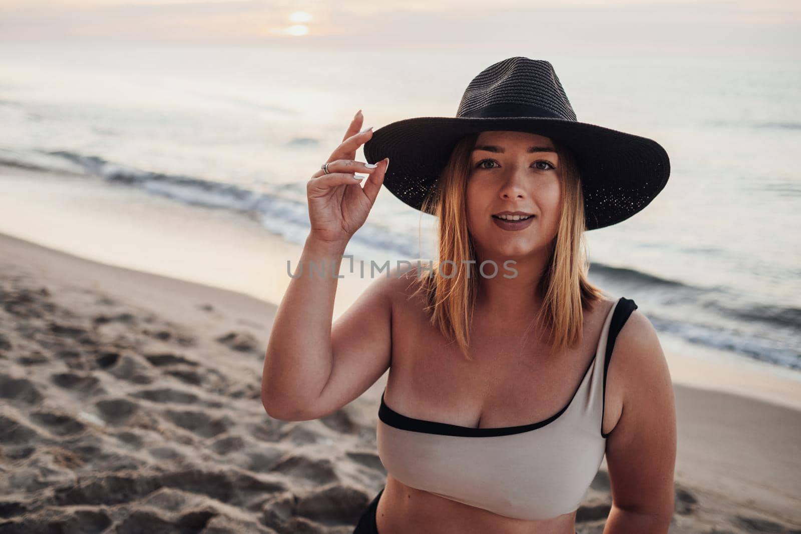 Close Up Portrait of Young Caucasian Woman Looking Towards the Camera While Standing on Sandy Beach at Early Morning