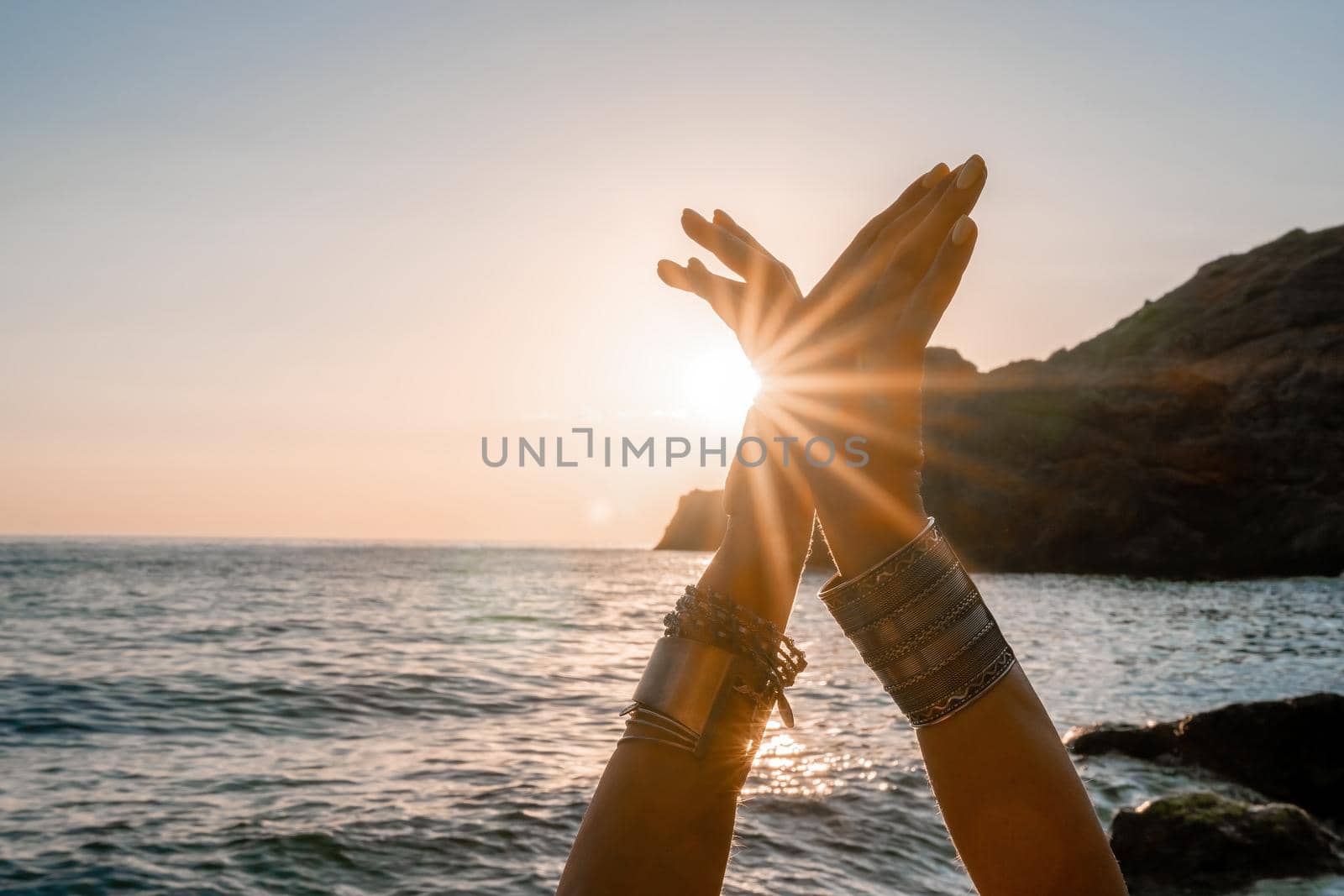 Young woman in swimsuit with long hair practicing stretching outdoors on yoga mat by the sea on a sunny day. Women's yoga fitness pilates routine. Healthy lifestyle, harmony and meditation concept.