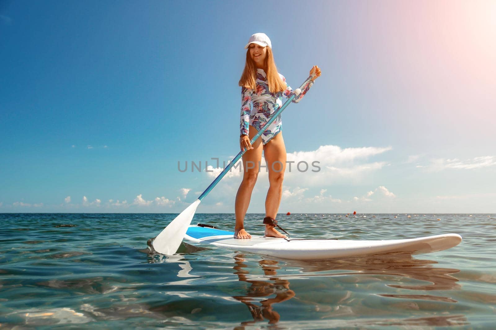 Healthy happy fit woman in bikini relaxing on a sup surfboard, floating on the clear turquoise sea water. Recreational Sports. Stand Up Paddle boarding. Summer fun, holidays travel. Active lifestyle by panophotograph