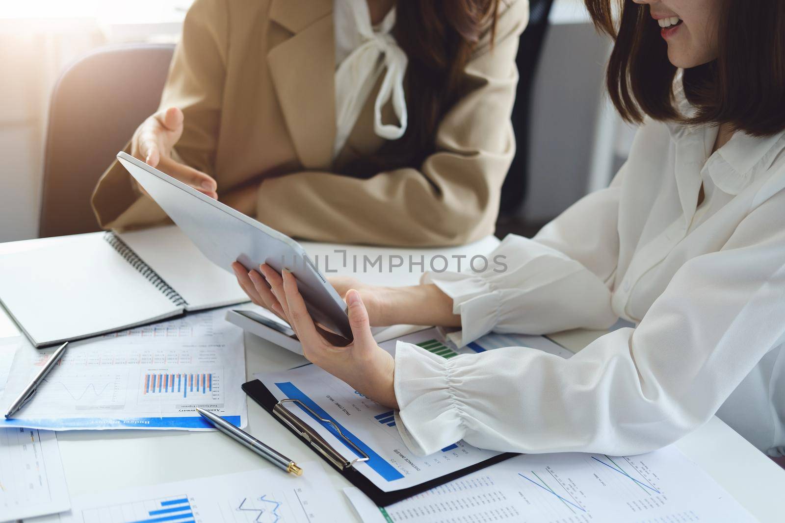 Negotiation, Analysis, Discussion, Asian women economist and marketer using tablet computer to plan investments and financial to prevent risks and losses for the company by Manastrong