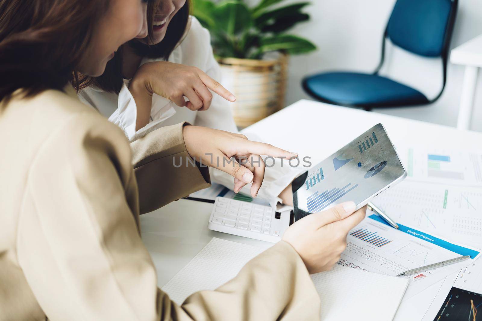 Negotiation, Analysis, Discussion, Asian women economist and marketer using tablet computer to plan investments and financial to prevent risks and losses for the company by Manastrong