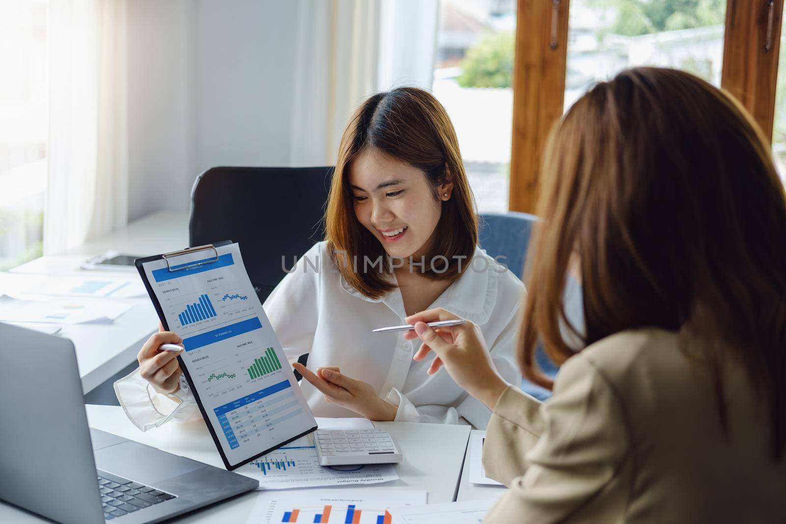 Negotiation, Analysis, Discussion, Asian woman economist and marketer pointing to a financial data sheet to plan investments to prevent risks and losses for the company.