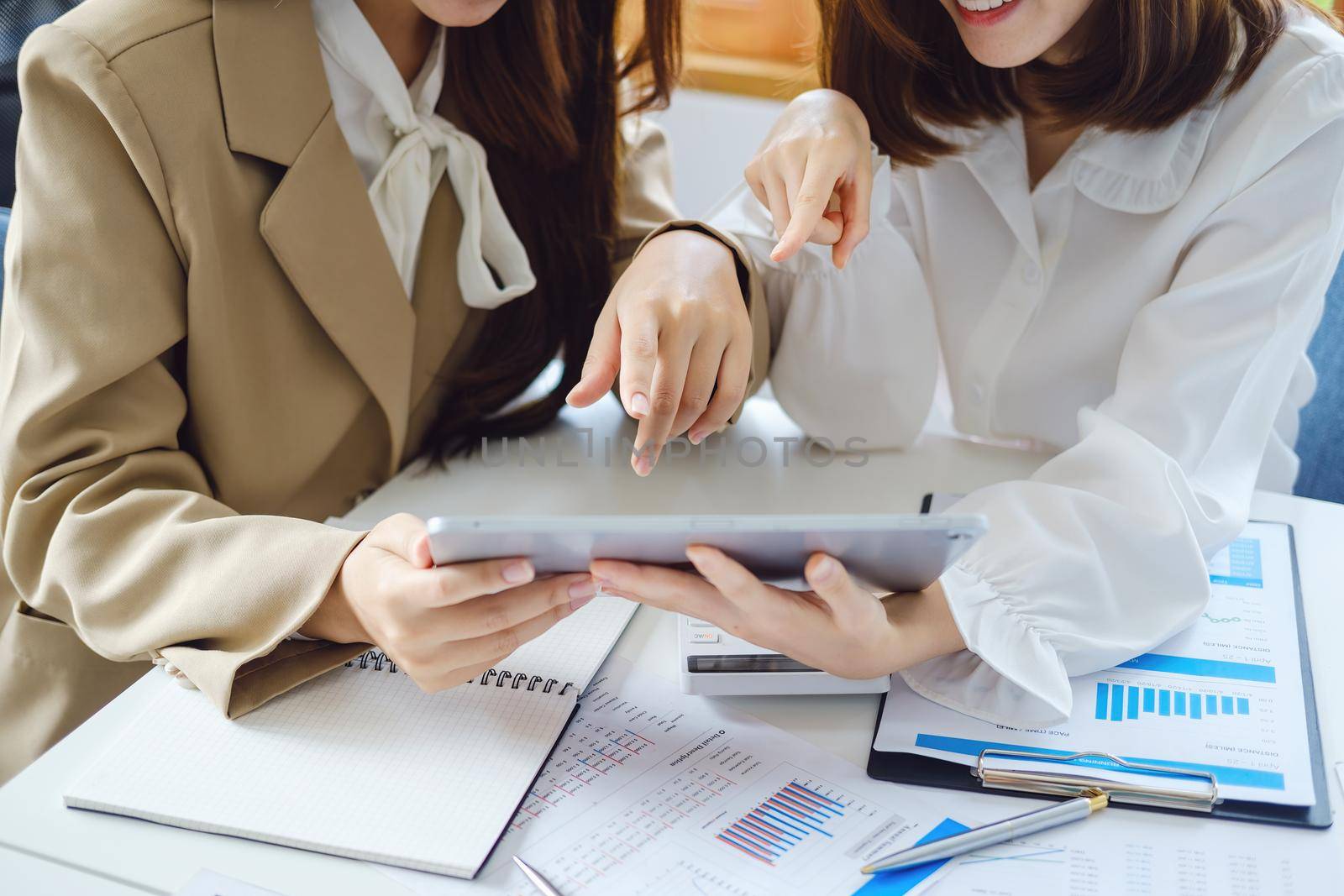 Negotiation, Analysis, Discussion, Asian women economist and marketer using tablet computer to plan investments and financial to prevent risks and losses for the company.