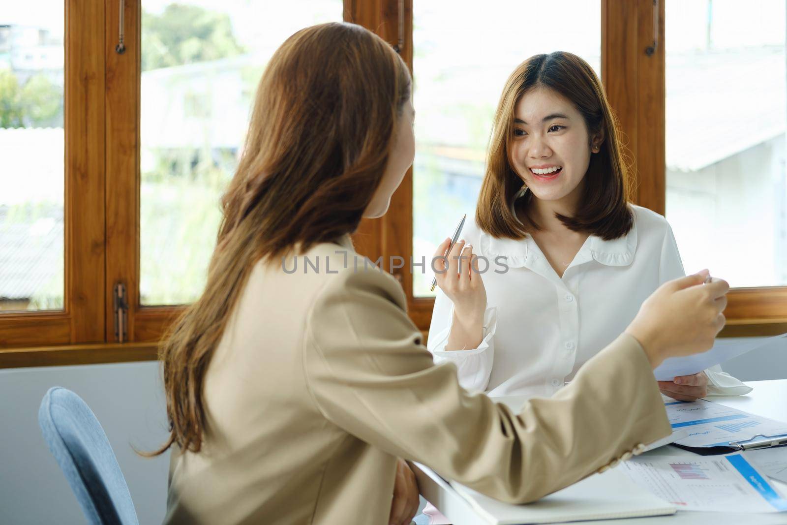 Negotiation, Analysis, Discussion, Portrait of an Asian woman economist and marketer pointing to a financial data sheet to plan investments to prevent risks and losses for the company by Manastrong