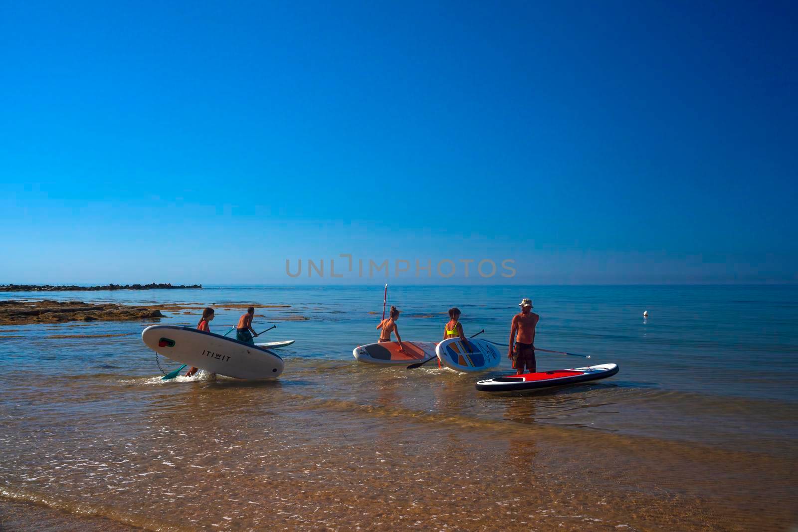 Realmonte, Italy - July 23,: Stand up paddle boarding. Joyful group of friendsare training SUP board in the mediterranean sea on a sunny morning in Realmonte beach on July 23, 2021