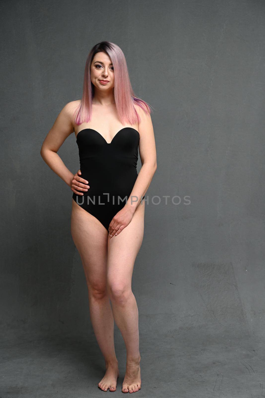 Pretty adult woman in full length in bodysuit looking directly at the camera