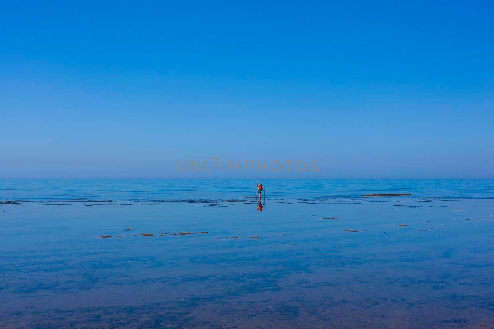 Scenic view of Sicily sea where an elderly man fishing with sticks