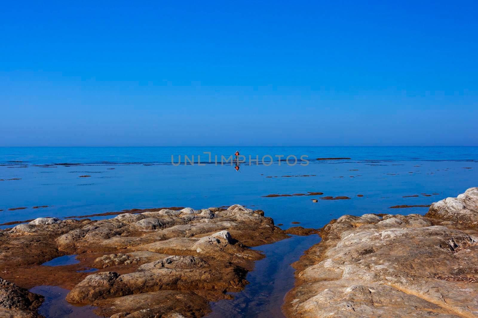 Scenic view of Sicily sea where an elderly man fishing with sticks