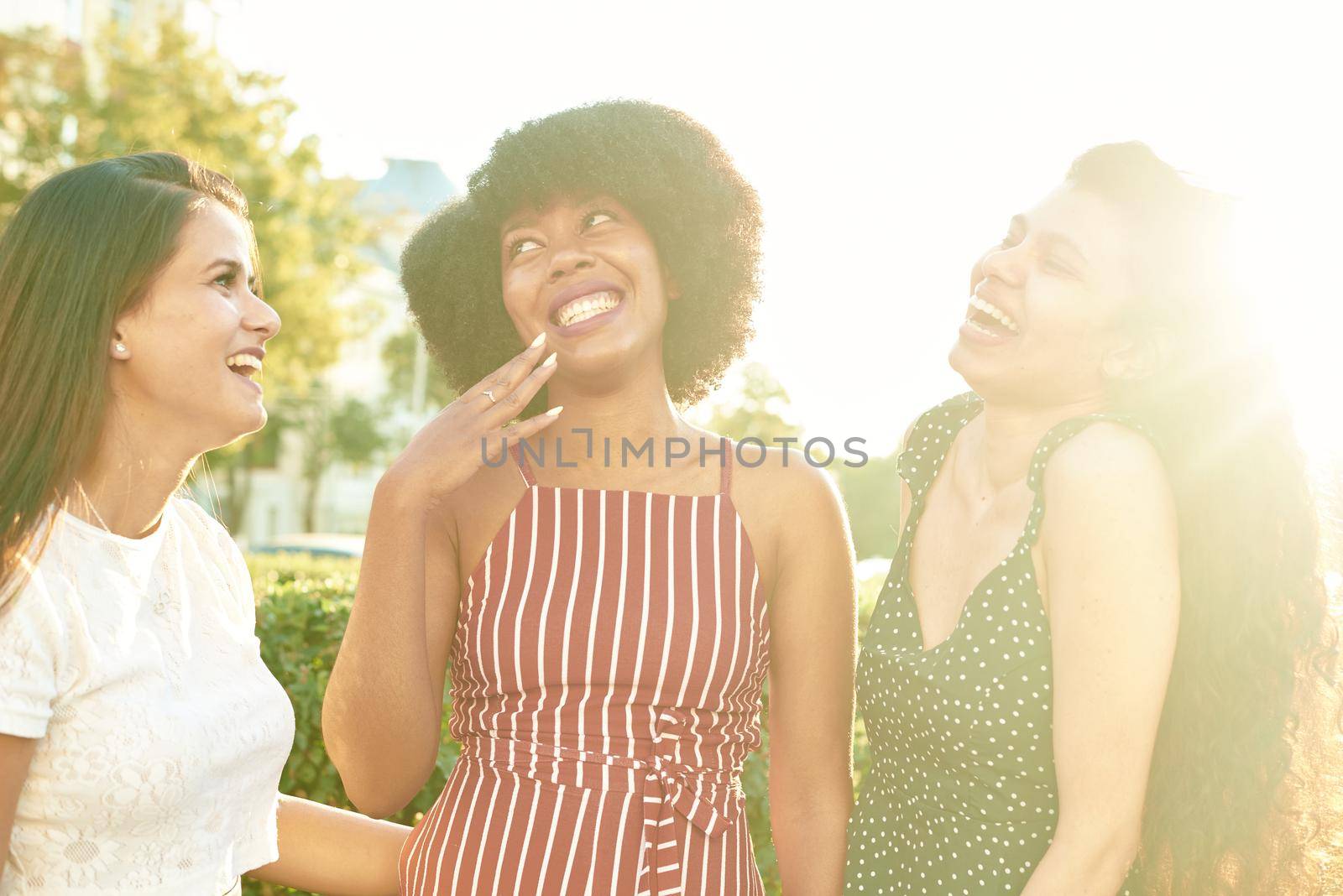 Three beautiful smiling girlfriends. Multi ethnic group of women staying outdoors by the city street and smiling.
