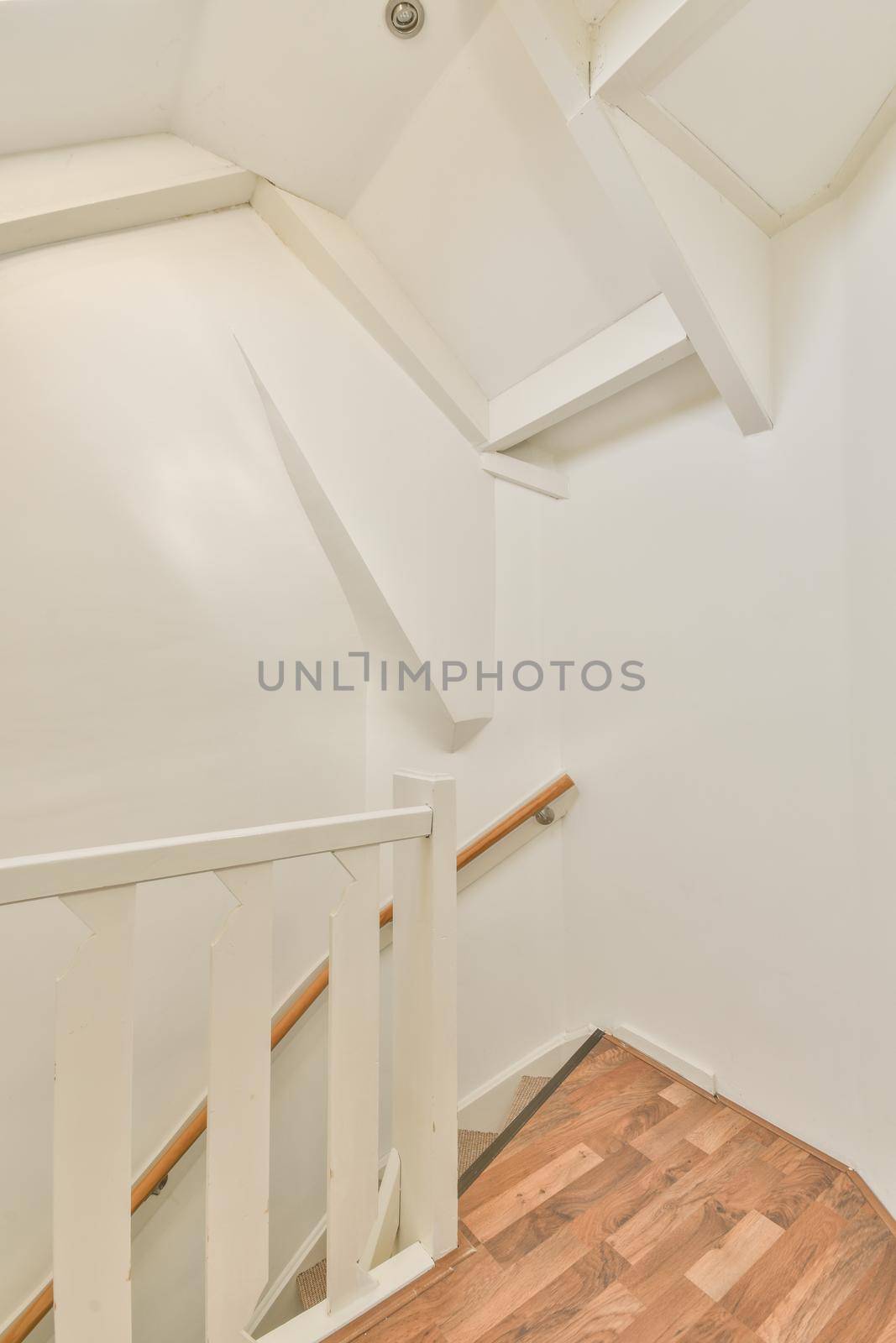 White spiral stairway connecting levels of contemporary house with wooden floor and white walls