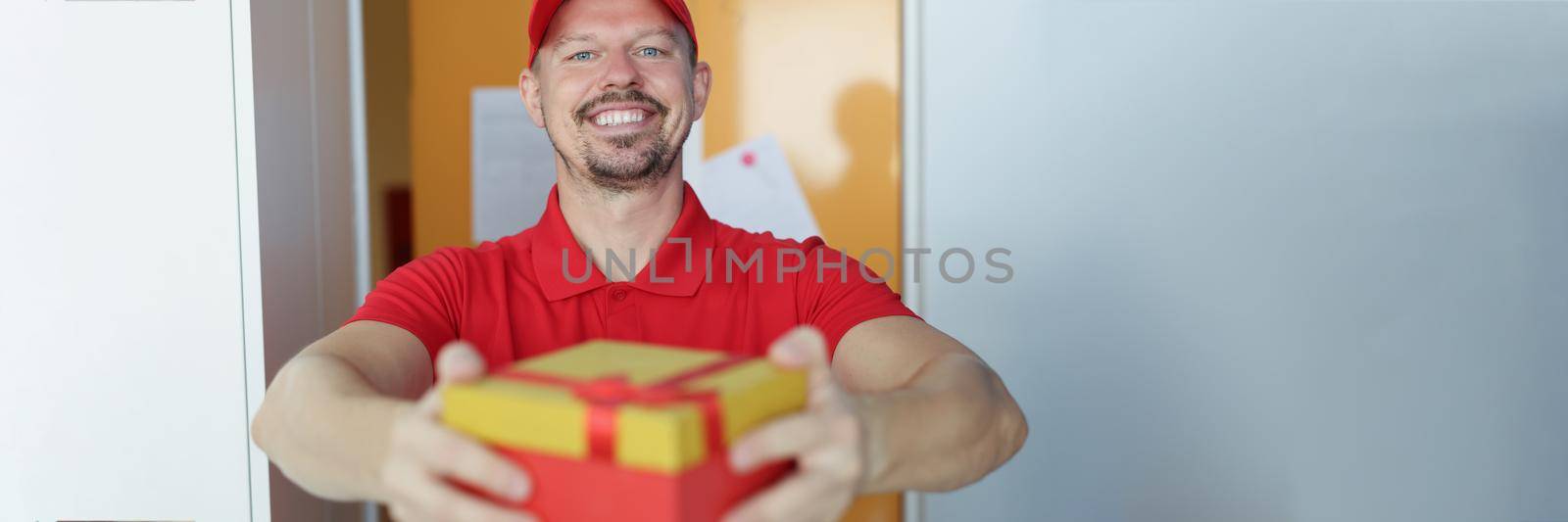 Portrait of smiling courier delivering package to owner, fast delivery service, gift box with red bow. Express delivery service, safe shipping, shipping worldwide concept