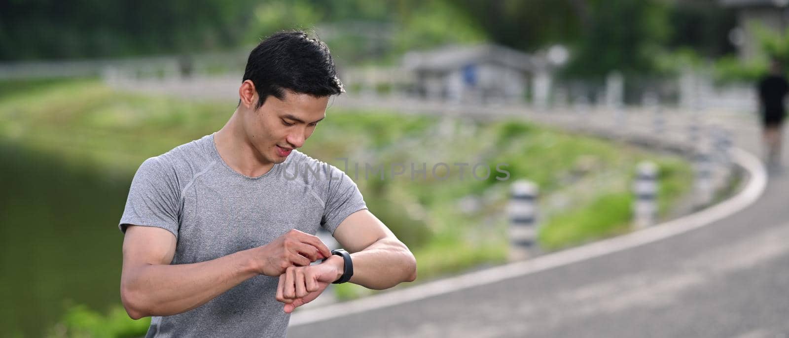 Sport man checking his heart rate data on smartwatch during morning workout in the park.