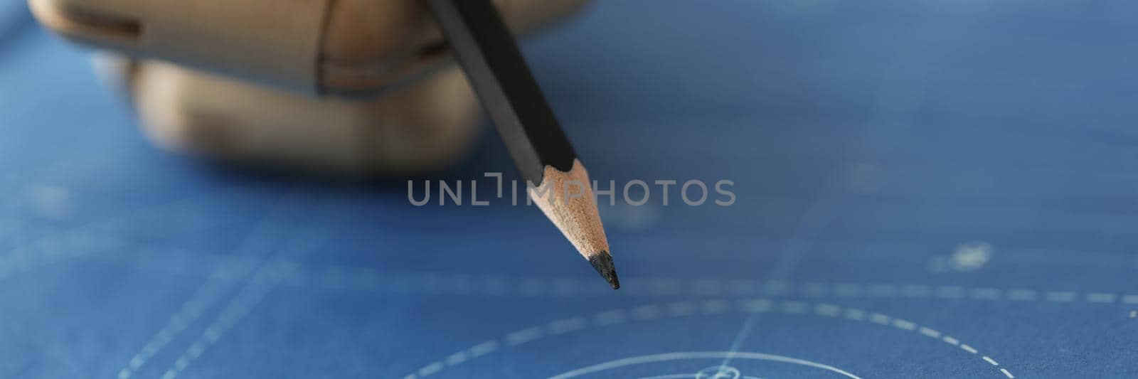 Close-up of wooden hand prosthesis holding pencil, drawing scheme, draft in process, making changes, planning project. Creative work, idea, construction, disability, business concept