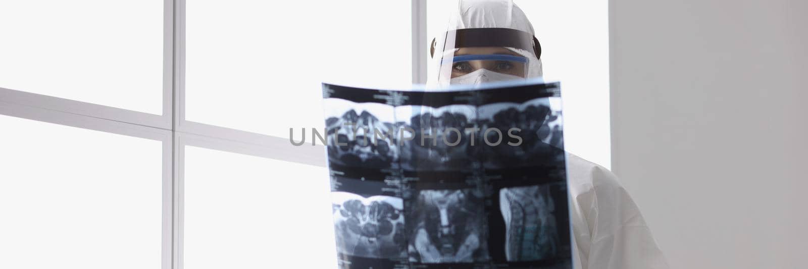 Close-up of qualified doctor observing radiograph of back, examine x ray in protective uniform. Film of patients analysis to find best solution for operation. Medicine, healthcare concept