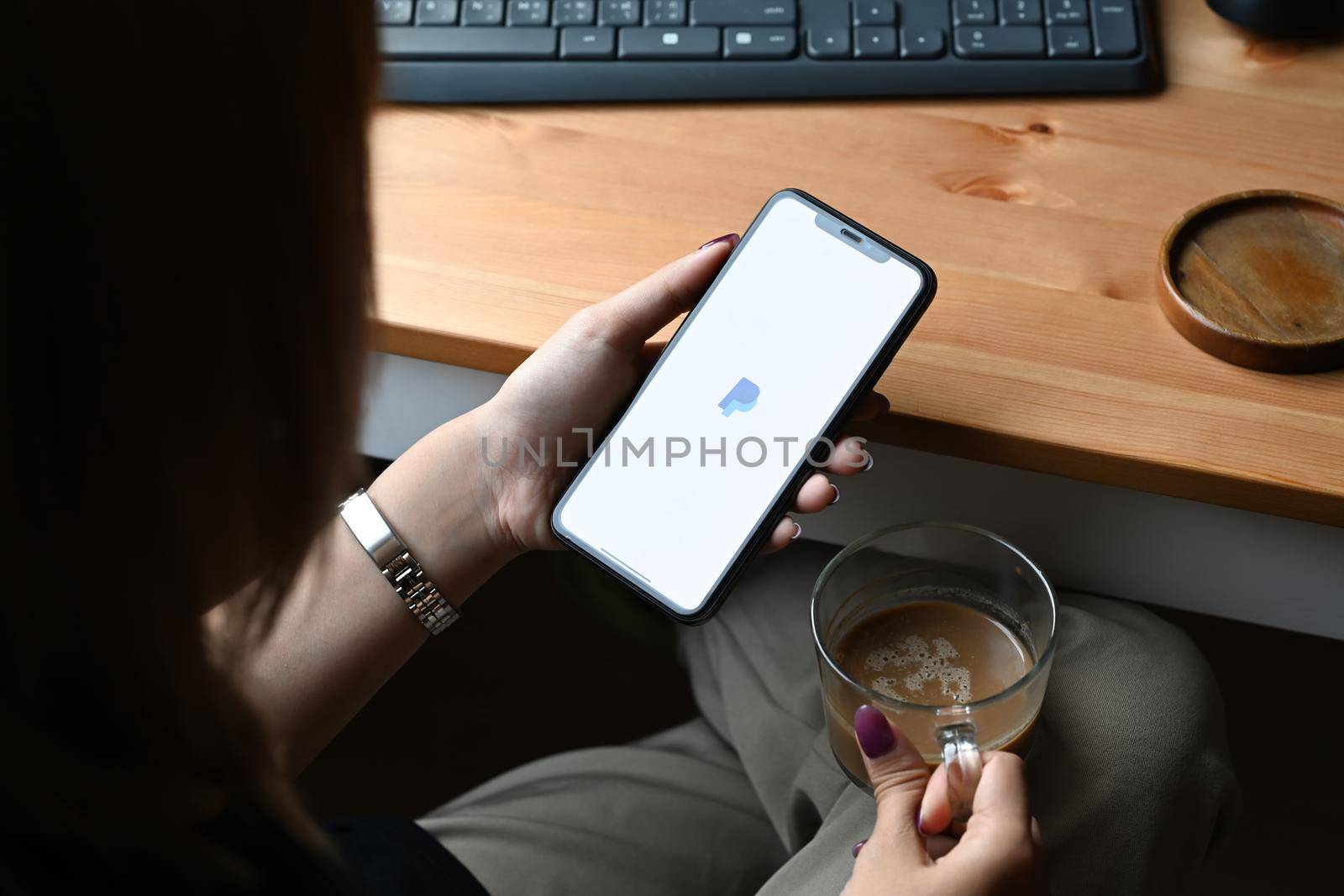 Chiang Mai, Thailand - Mar 01,2022: Woman holding iPhone 11 Pro Max with PayPal app on screen. PayPal is an internet based digital money transfer service.