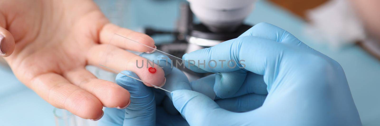 Close-up of medical worker draw blood from patients finger, blood test in hospital. Measurement of blood sugar level, worker in gloves, special equipment for procedure. Medicine concept