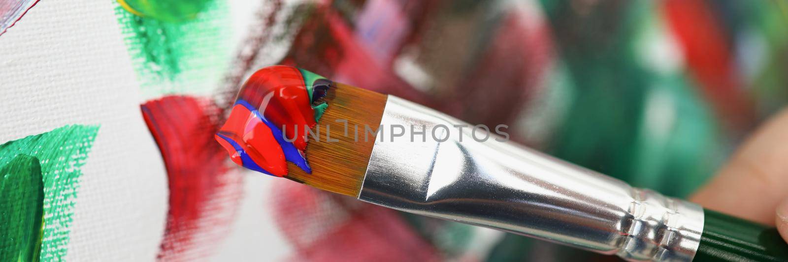 Close-up of abstract oil painted art, painter holding brush with red paint, equipment for painting. Express mood on canvas, flow of imagination. Creativity, art, hobby, artist concept