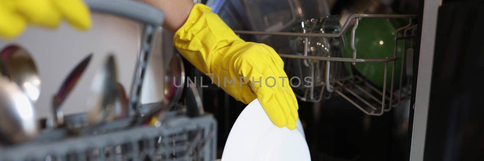 Close-up of woman loading dishwasher, open dishwasher with clean plates after washing. Modern kitchen machine to keep tableware clean. Housework, domestic chores, cleaning concept