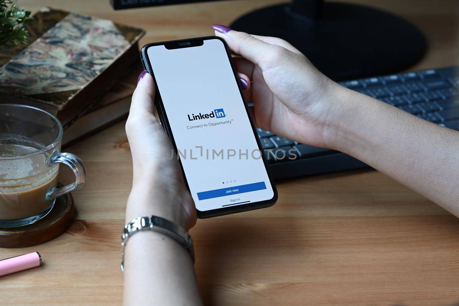 Chiang Mai, Thailand - Mar 01,2022: Woman holding smart phone with LinkedIn app. LinkedIn is a social network for the business community.