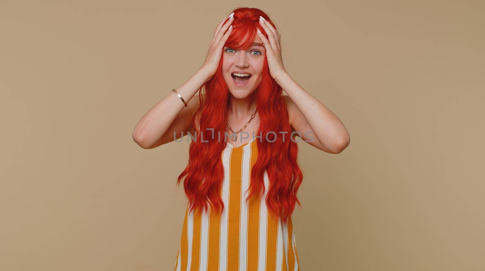 Redhead woman in tank top screams from stress tension problems feels horror hopelessness fear surprise shock expresses gestures rage. Young ginger girl isolated alone on beige studio wall background