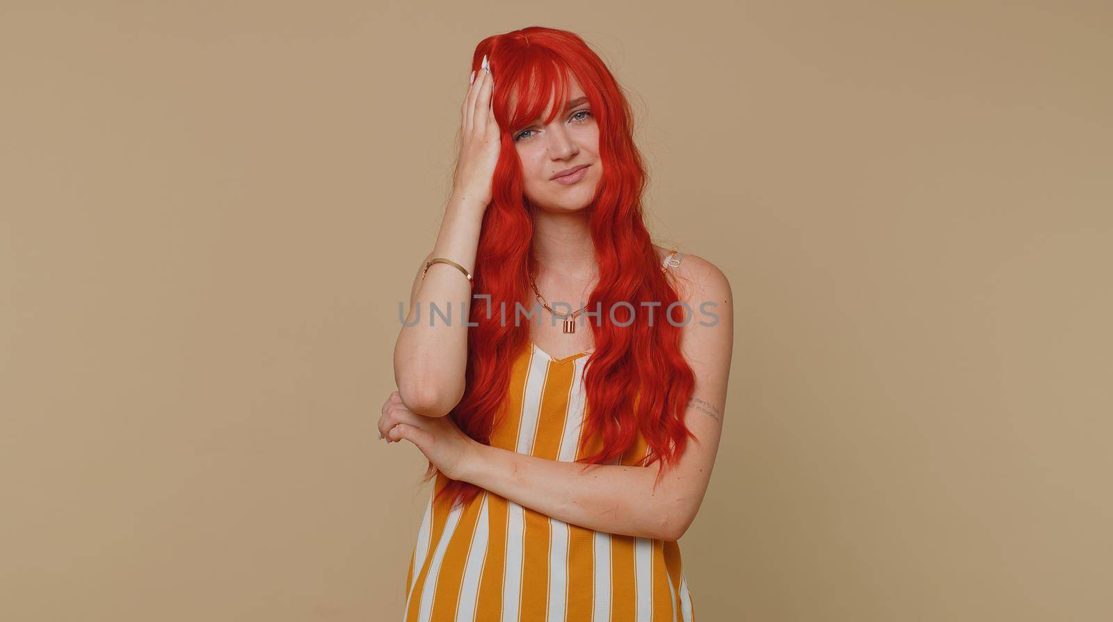 Red hair young woman in tank top rubbing temples to cure headache problem, suffering from tension and migaine, stress, grimacing in pain, high blood pressure. Girl isolated alone on beige background