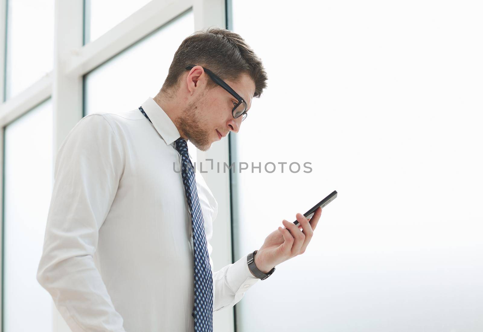 Businessman using smart phone in blurred office space background and copy space