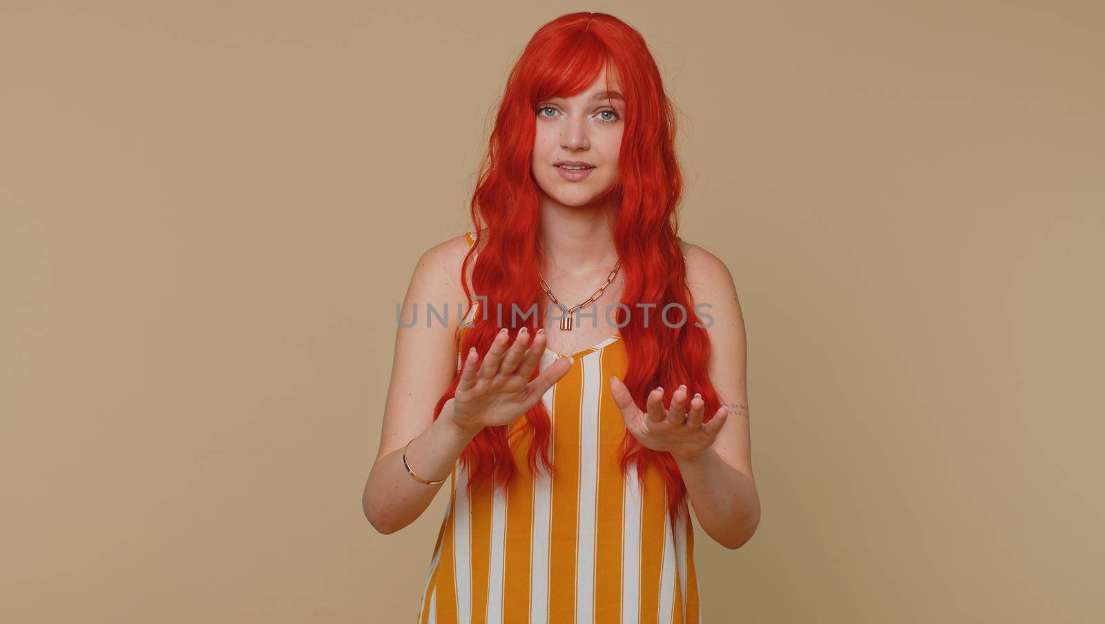 Hey you, be careful. Woman warning with admonishing finger gesture, saying no, be careful, scolding and giving advice to avoid danger, disapproval sign. Ginger girl isolated on beige studio background