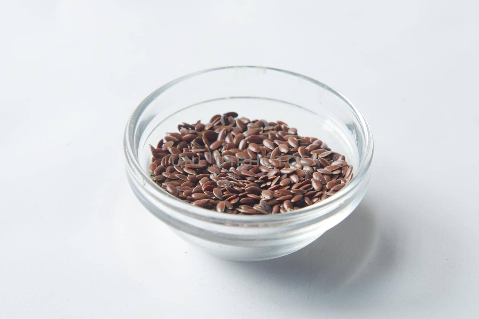 close up of flax seeds on in a glass bowl on white ,