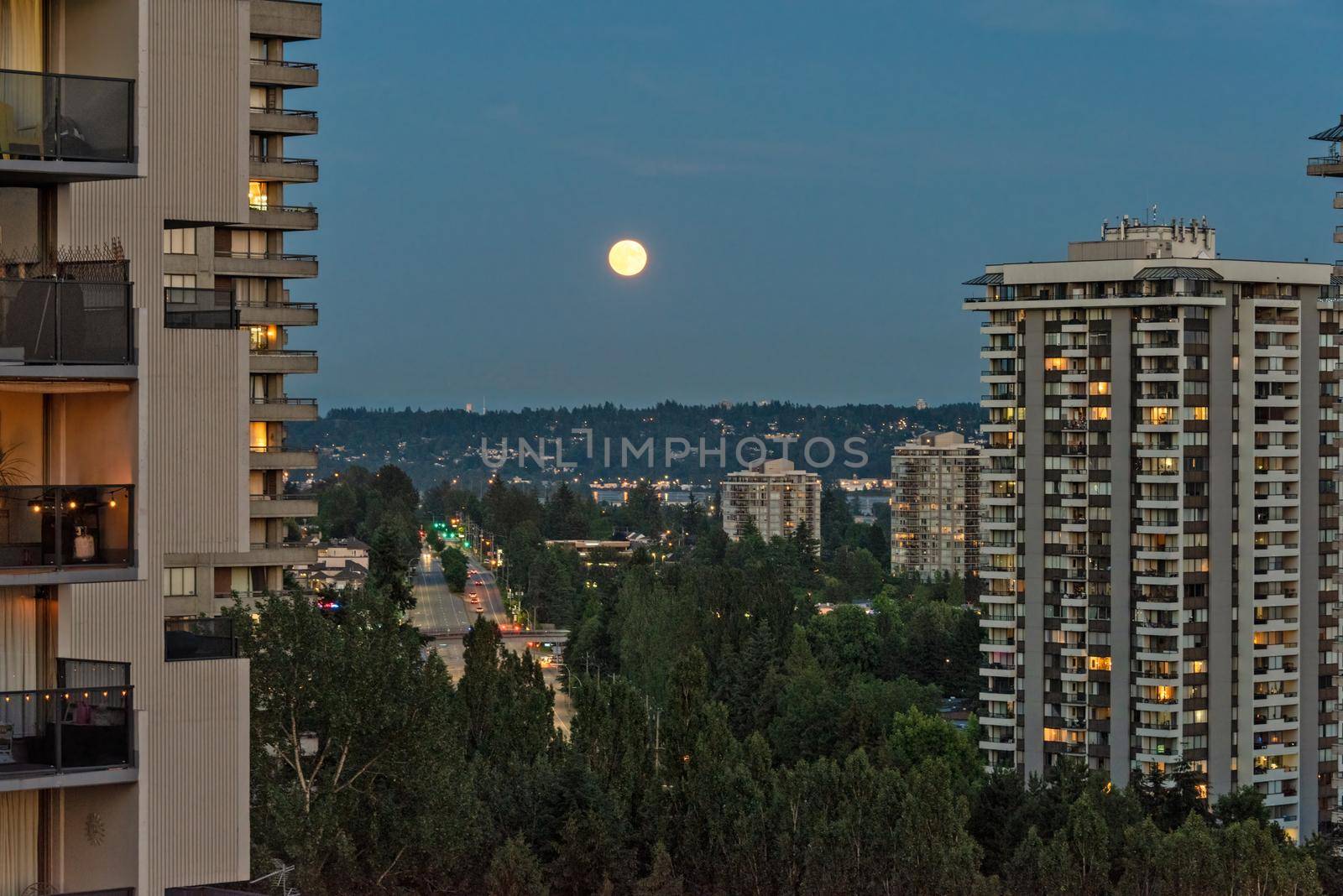 Full yellow moon raising over night city.