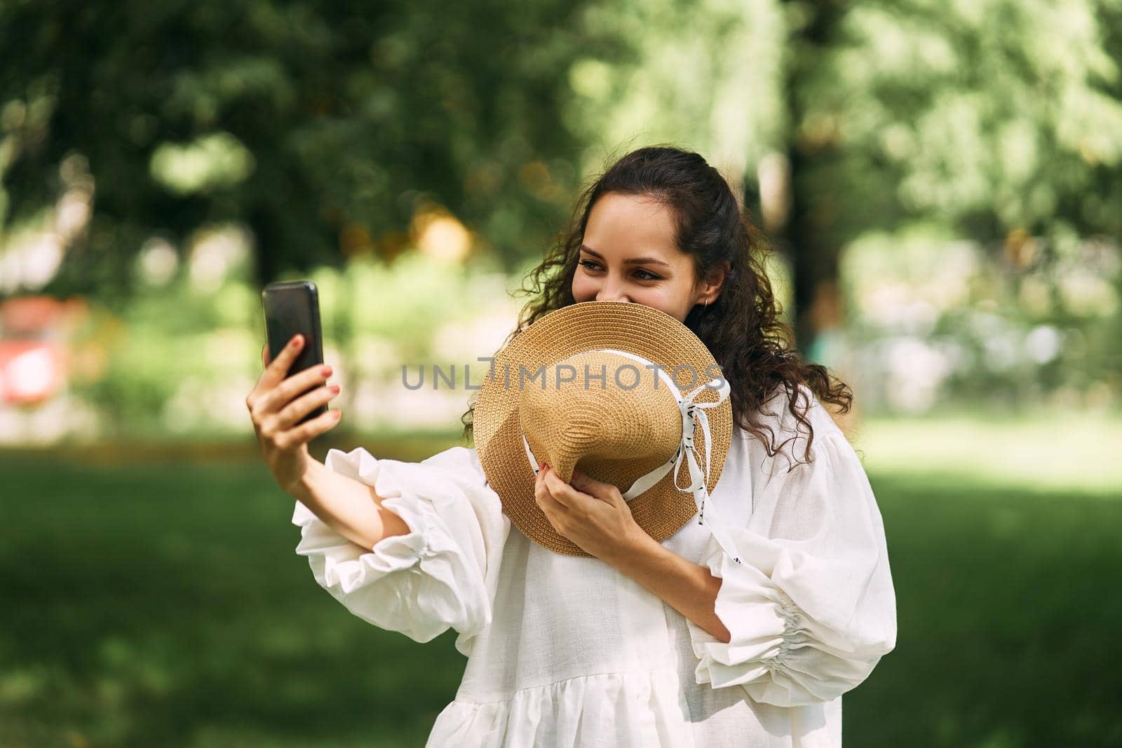 Young beautiful girl in a hat makes a selfie on her phone in the park. High quality photo