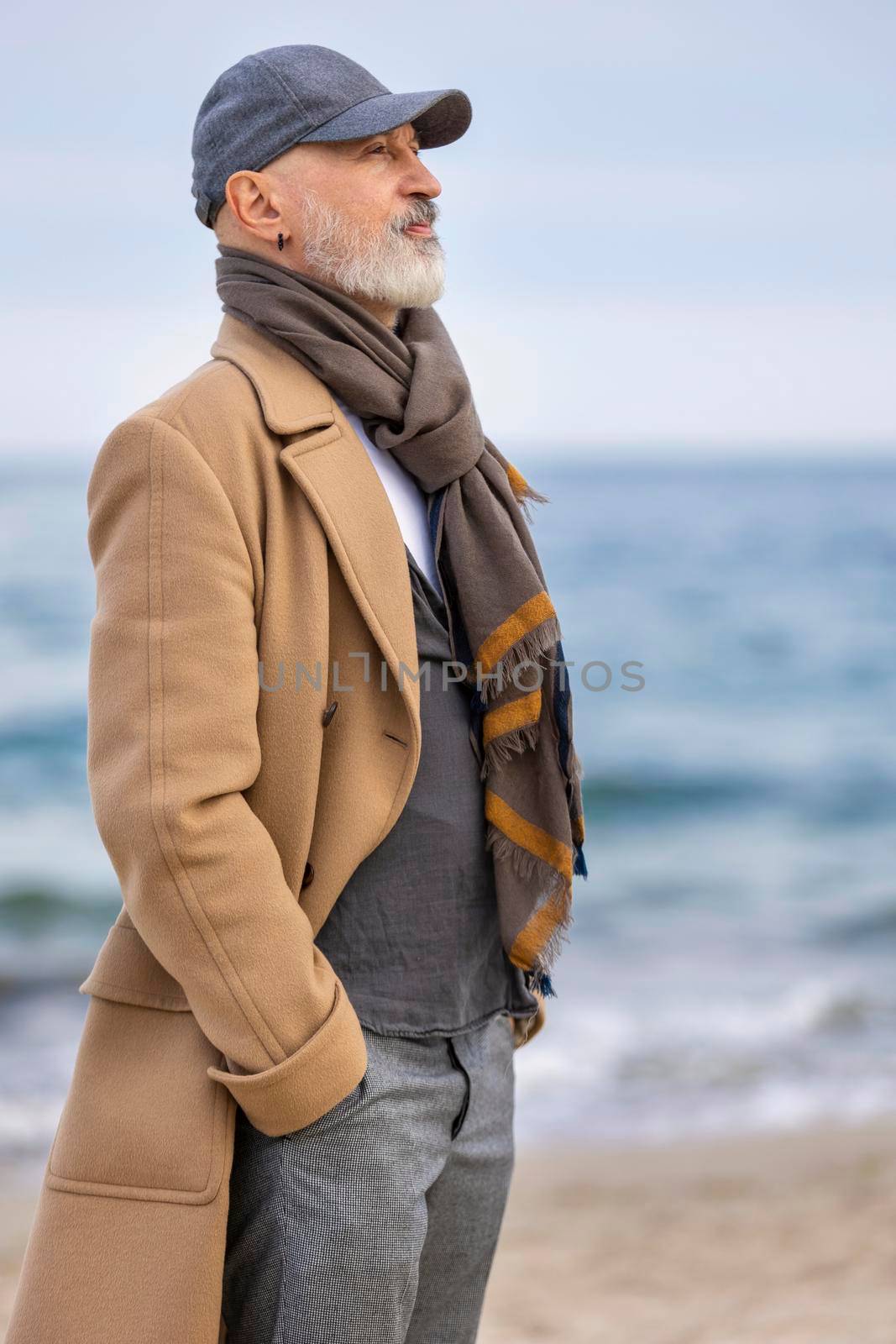 an aged man walking along the beach against the background of the sea