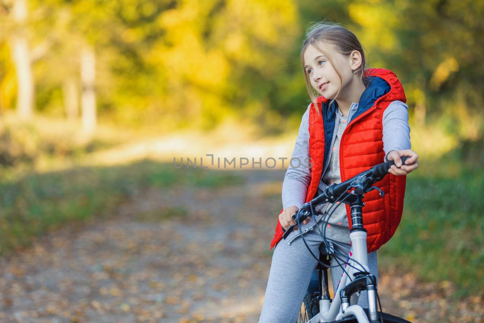 portrait of a girl with a bicycle on the background of an autumn forest