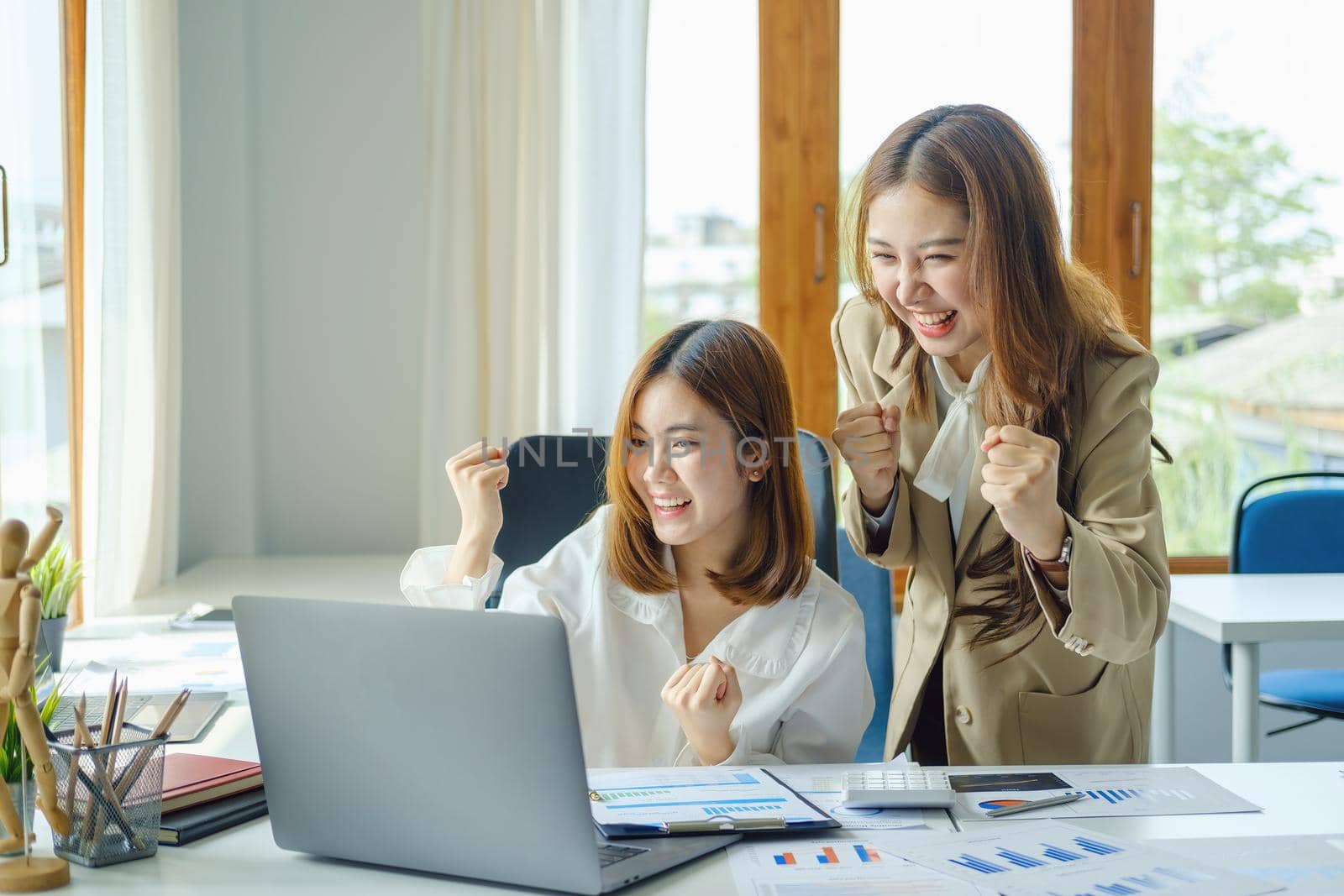 startup, successful, portrait of two young Asian women working on laptop computers, delighted with sales targets planned marketing by Manastrong