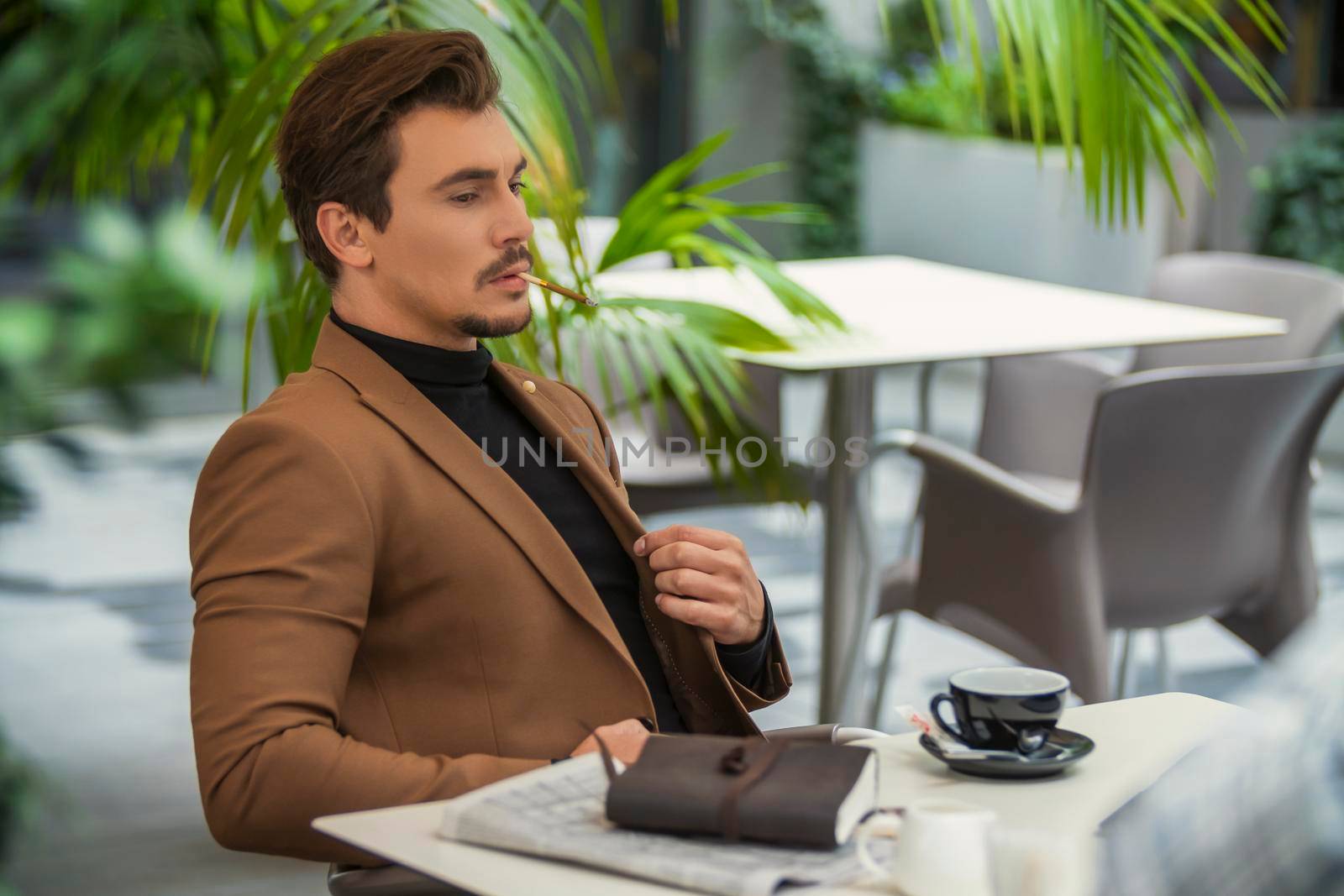 a man in a business suit sits at a table and smokes