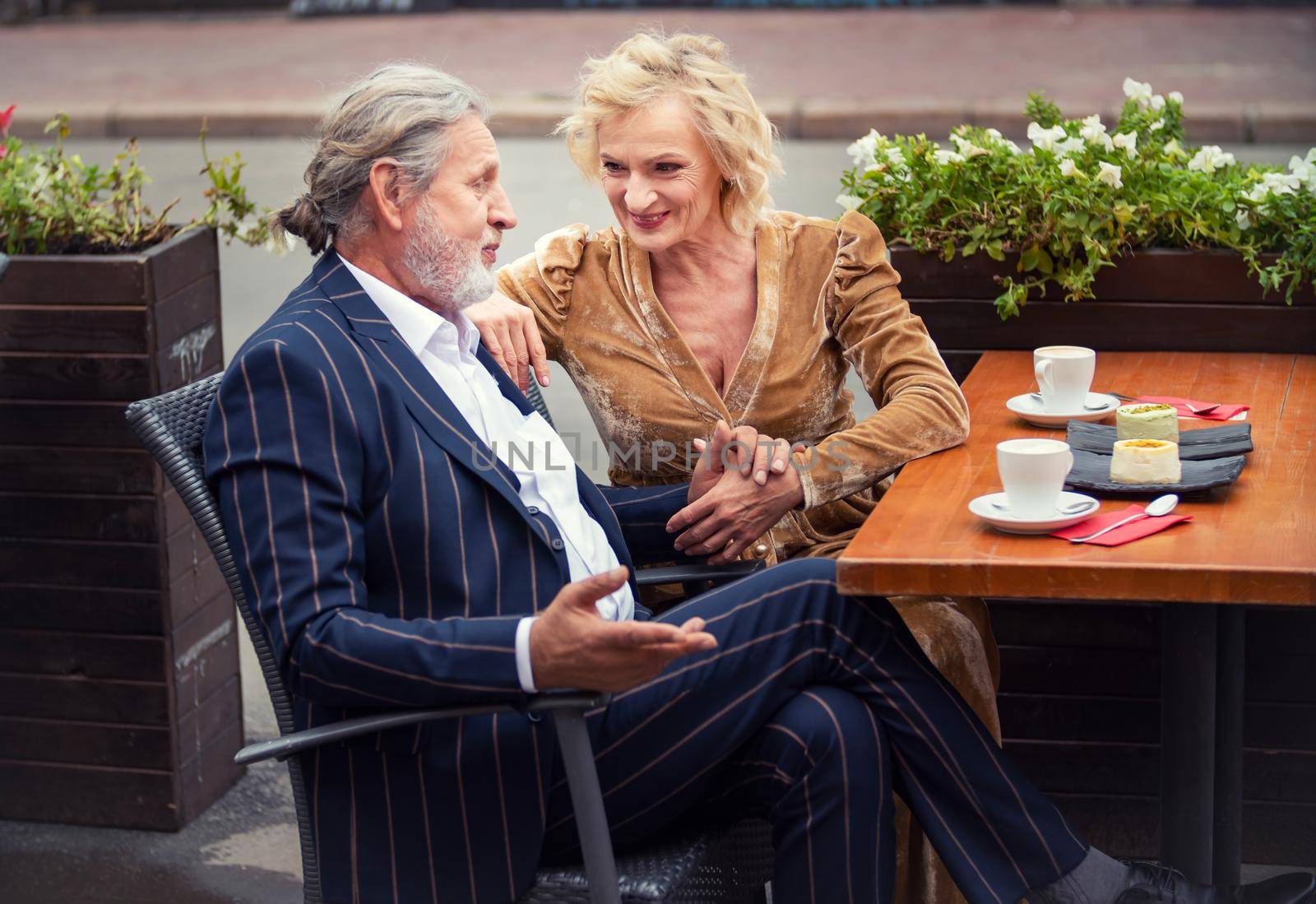 elderly couple sitting at a table on the street