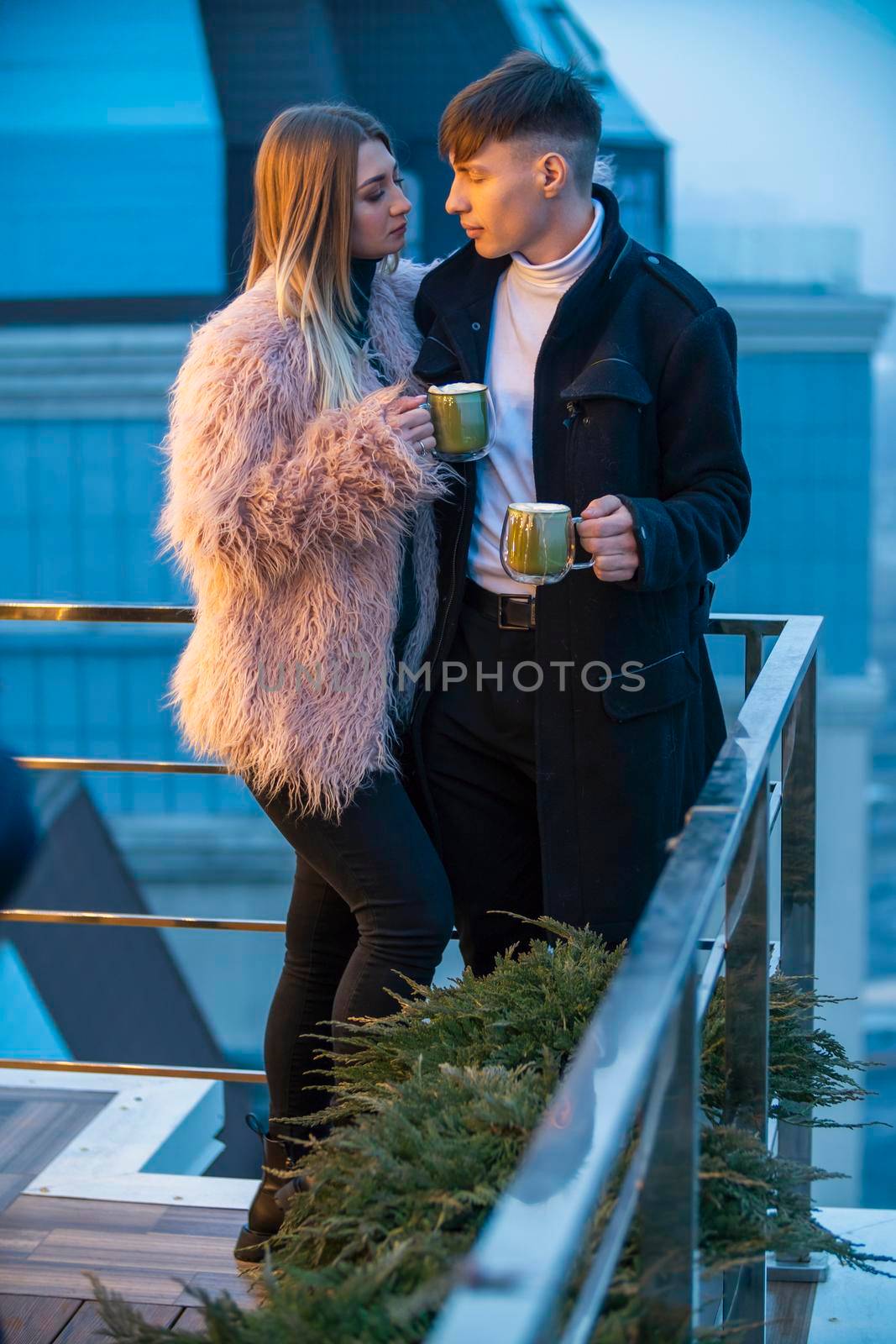 couple with mugs on the terrace of a high-rise building by zokov