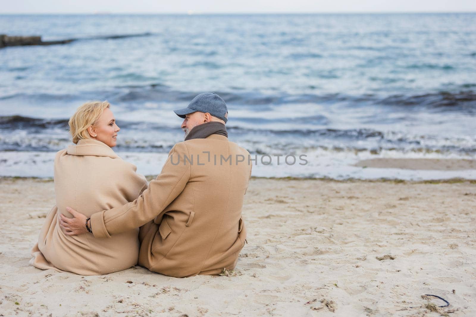 aged couple sitting on the beach near the sea