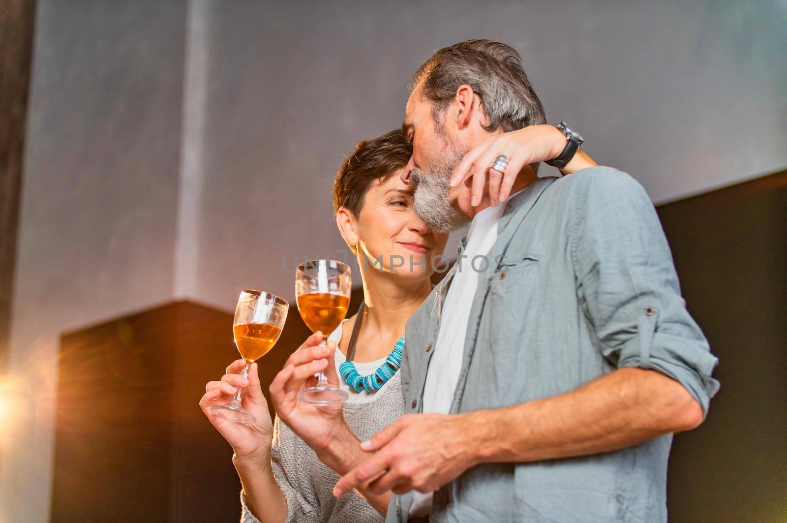 aged couple with glasses of wine in the kitchen
