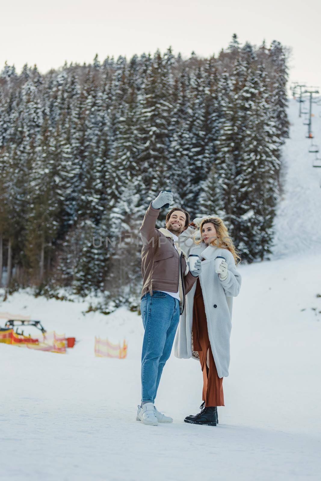 young couple taking a selfie on the background of a snowy mountain