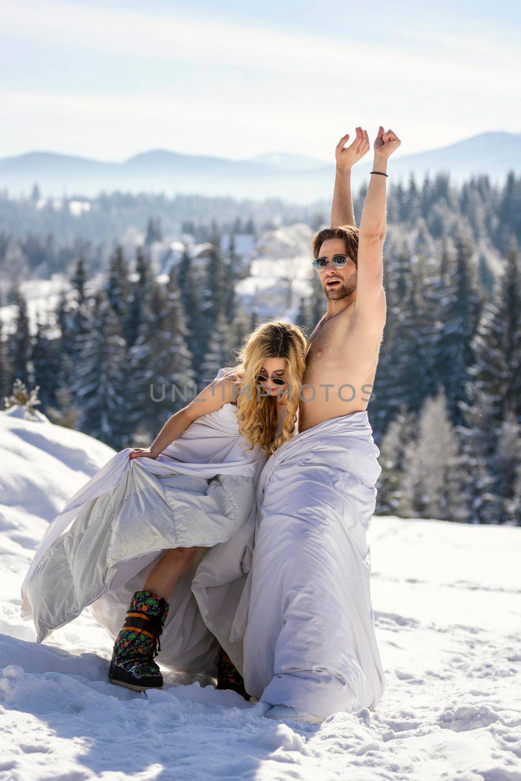 couple in blankets in winter on the background of forest and mountains