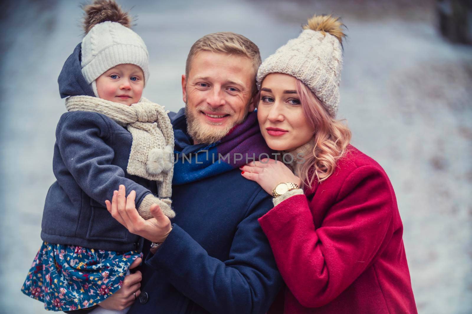 portrait of a family with a child in their arms against the background of a snowy forest